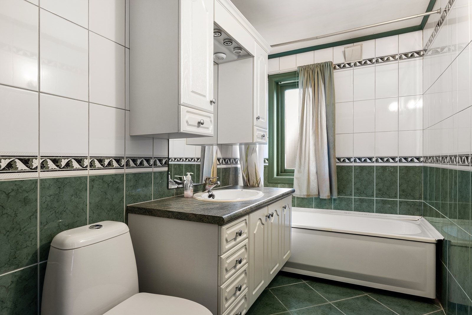 Romslig baderom med badekar og flislagte overflater. Galleribilde