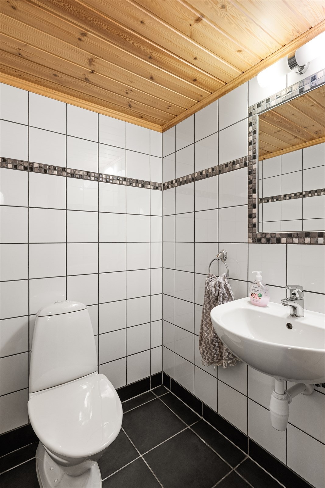 Lyst og praktisk WC med flislagte overflater. Galleribilde