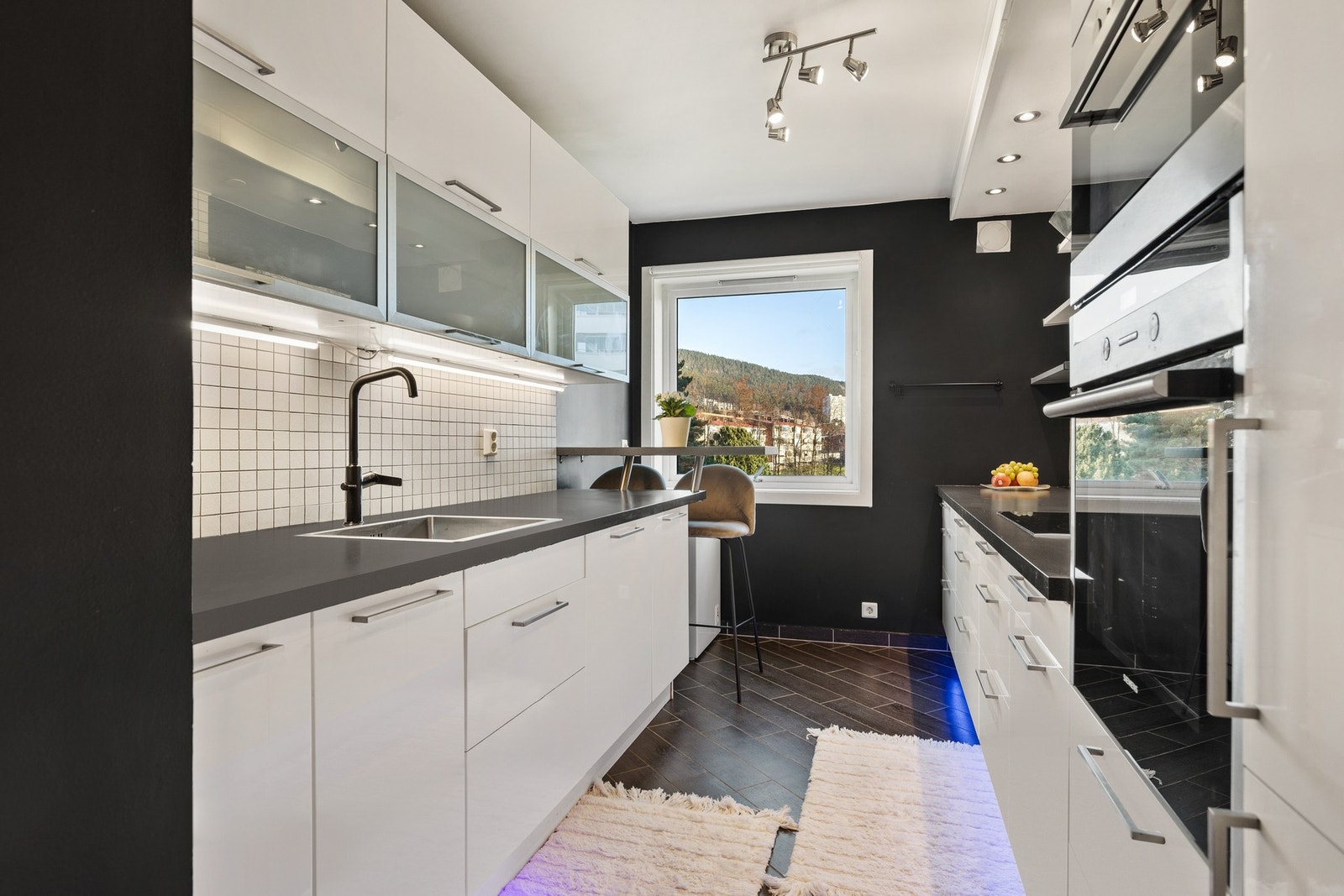 Leiligheten har et moderne uttrykk med pene overflater, downlights i himling og pent kjøkken med integrerte hvitevarer Galleribilde