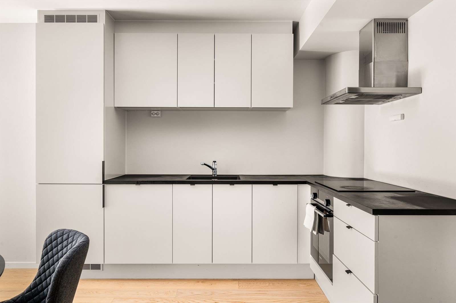 Kjøkkeninnredning med slette fronter og rikelig oppbevaringsplass i over og underskap. Gode arbeidsflater på benkeplate med plass til matlaging og annet. På kjøkken er det integrert stekeovn, platetopp, oppvaskmaskin samt kombinert kjøle-og fryseskap. Galleribilde