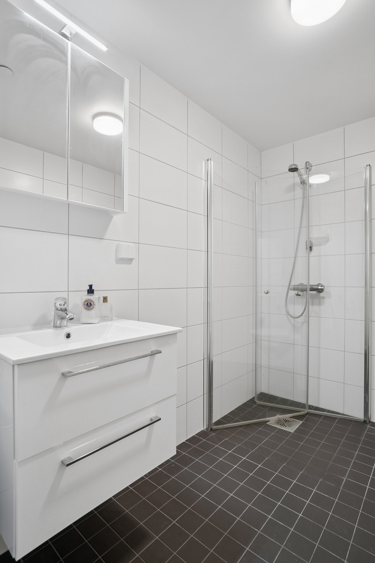 Lys innredning med heldekkende servantplate, speil, dusjnisje og WC: Galleribilde