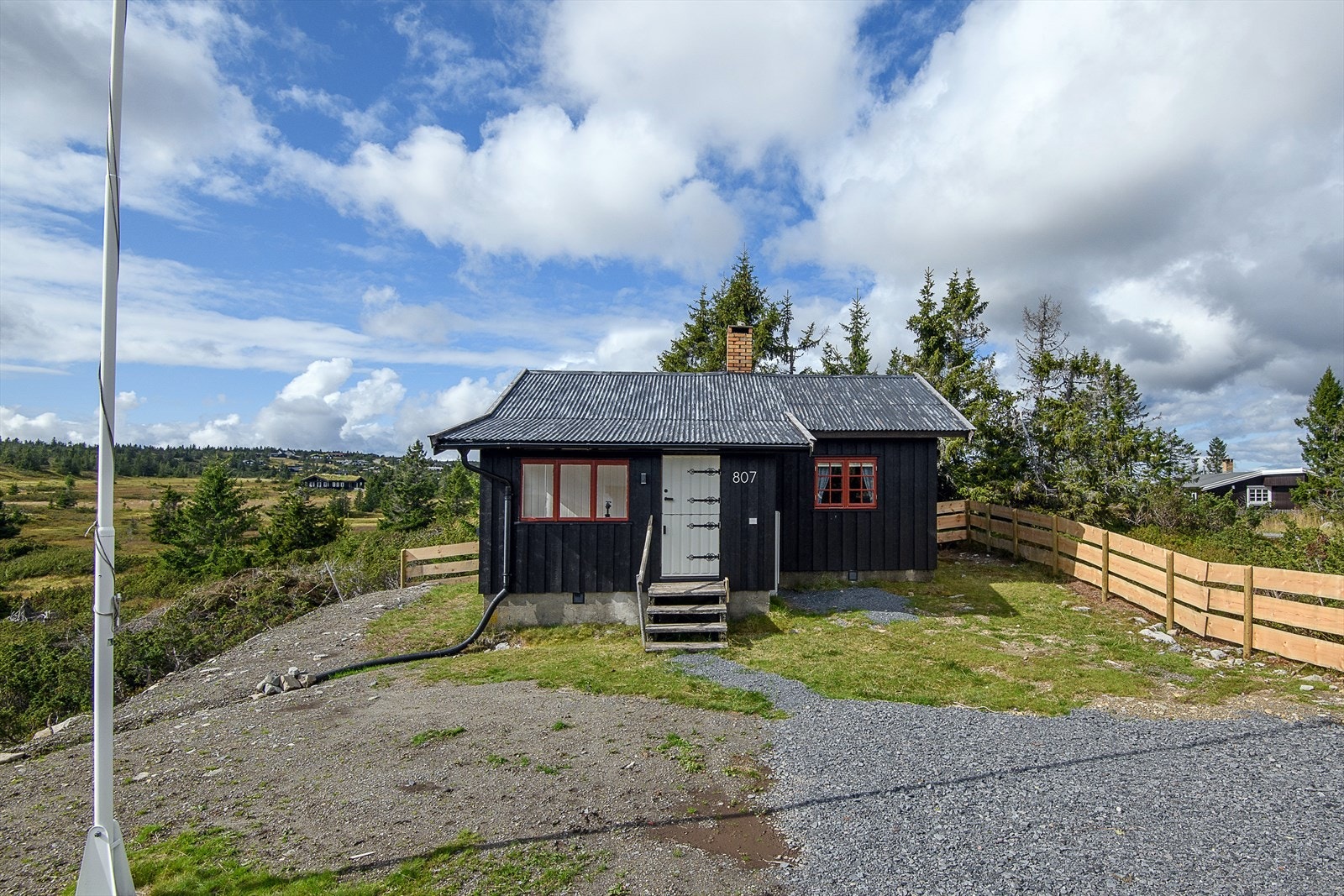 Gruset gårdsplass og biloppstillingsplass. Tomten er delvis inngjerdet. Galleribilde