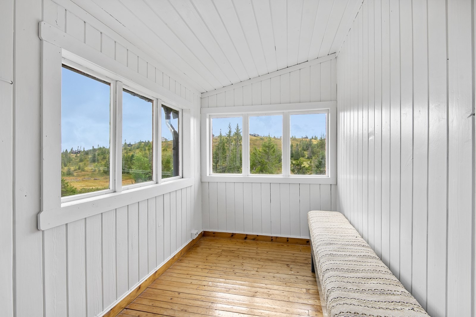 Lysmalt og trivelig verandastue i forbindelse med inngangen. Her kan en sitte skjermet for vær og vind og allikevel nyte utsikten. Galleribilde