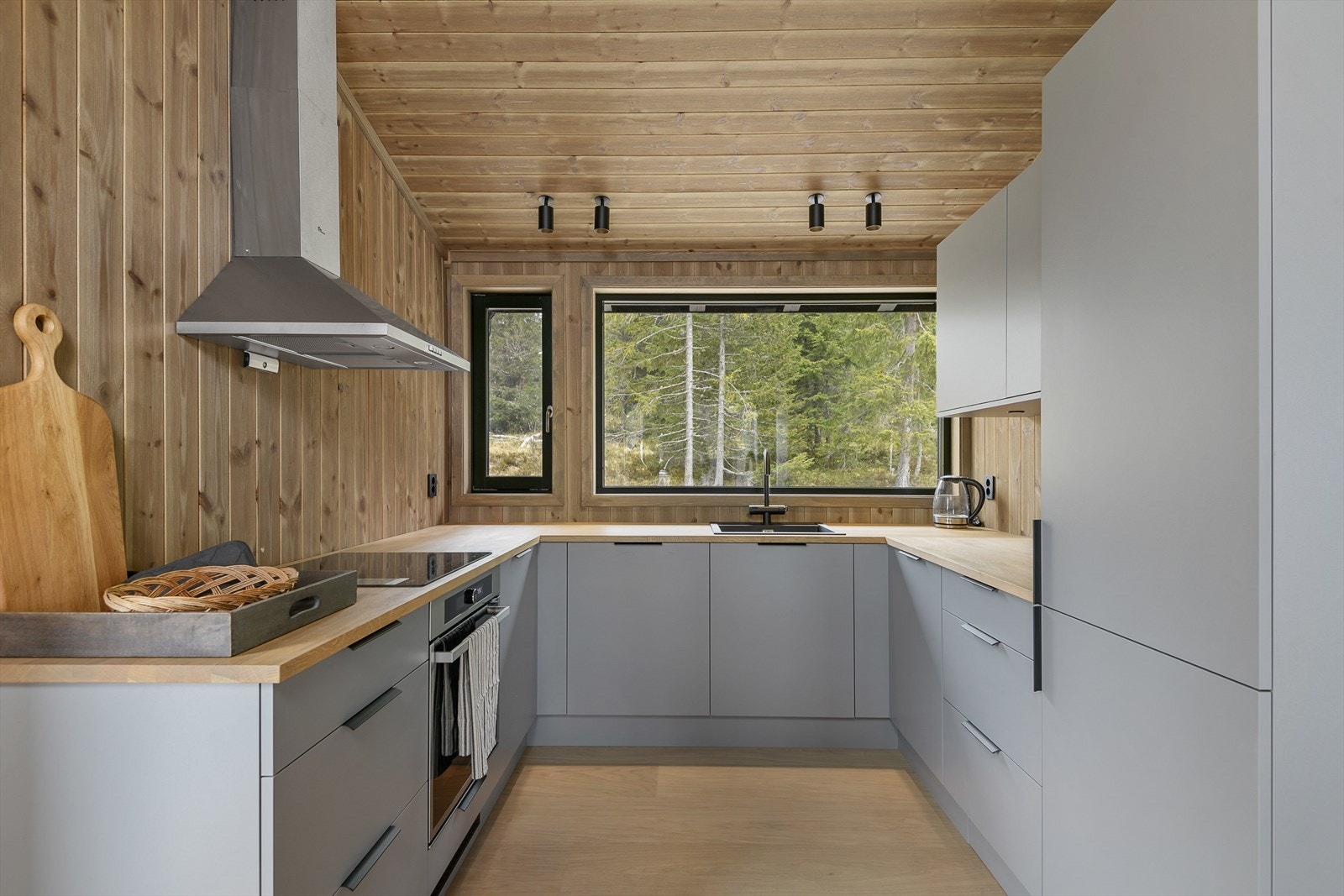 Moderne, funksjonelt kjøkken med glatte, fronter i en delikat og tidløs gråtone. Kjøkkenet har U-form og godt med skapplass. Fint lys inn gjennom vindu over kjøkkenbenken. Galleribilde