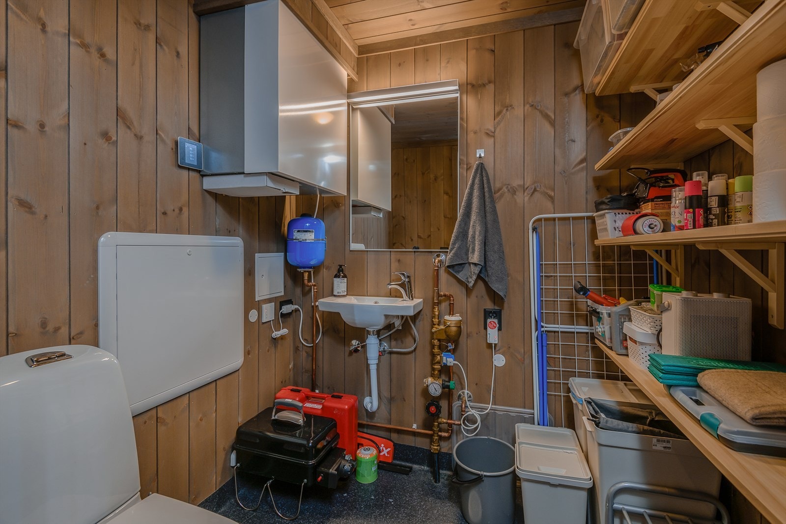 Praktisk, kombinert wc og bod/teknisk rom er innredet med hyller for oppbevaring. Galleribilde