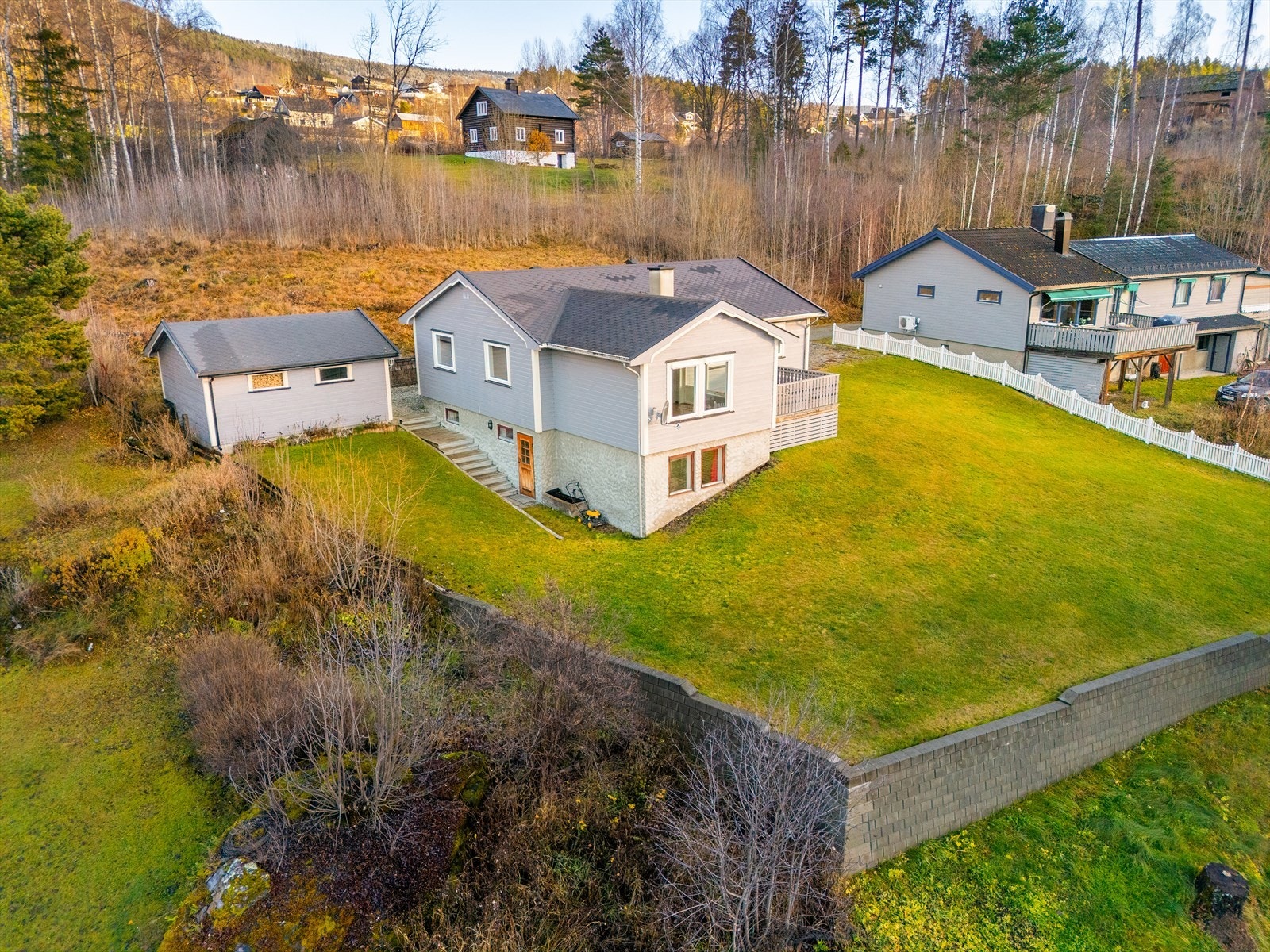 Det er gjerde rundt deler av tomten, og støttemur nedenfor og ovenfor. Galleribilde