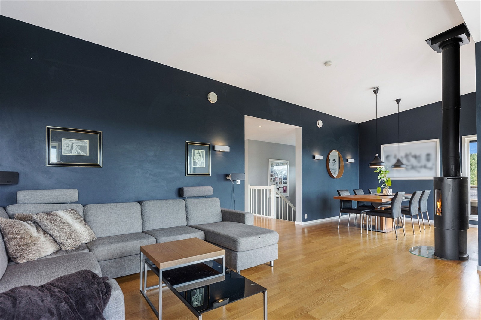 Rommet har god plass til både sofagruppe og spisebord. Peisovnen er strategisk plassert midt mellom. Galleribilde