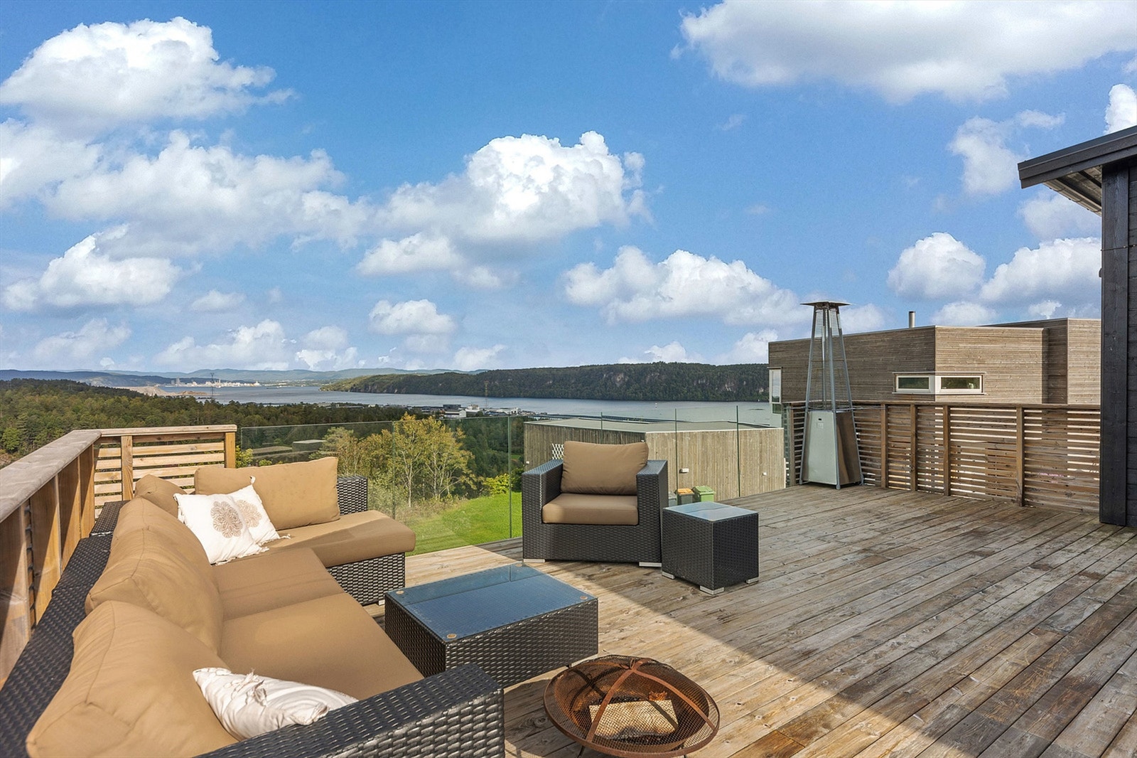 Den store terrassen utenfor stuen har rikelig med plass til flere sittegrupper. Rekkverk mot sjøen i glass for at utsikten kan nytes også når du sitter ned. Galleribilde