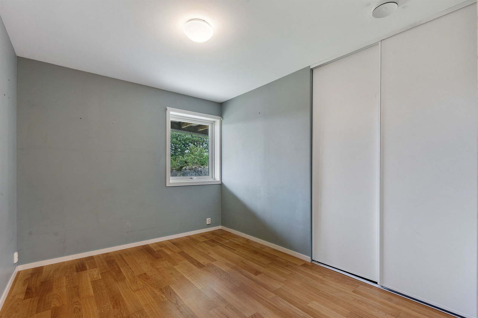 Boligens tredje soverom i første etasje, med plass til seng og skyvedørsgarderobe. Galleribilde