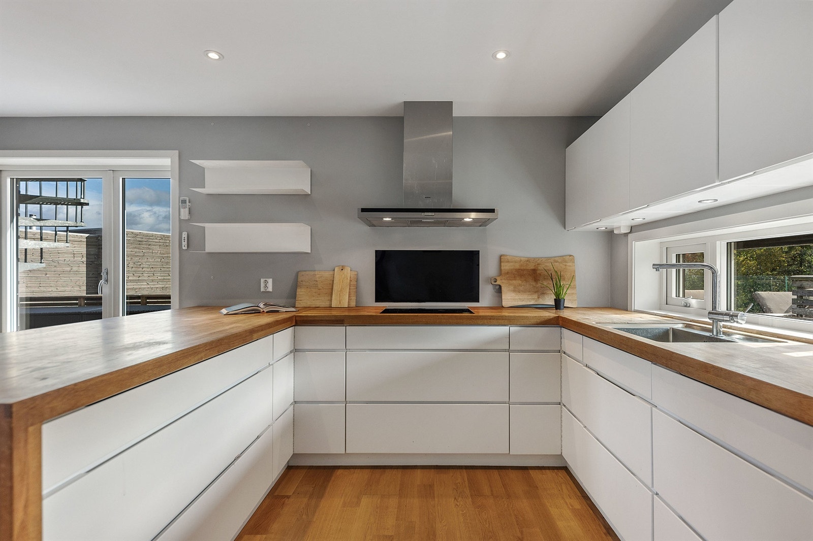 Kjøkkeninnredning fra Kvik i en arbeidsvennlig U-form med slette fronter og integrerte gripefelt. Galleribilde