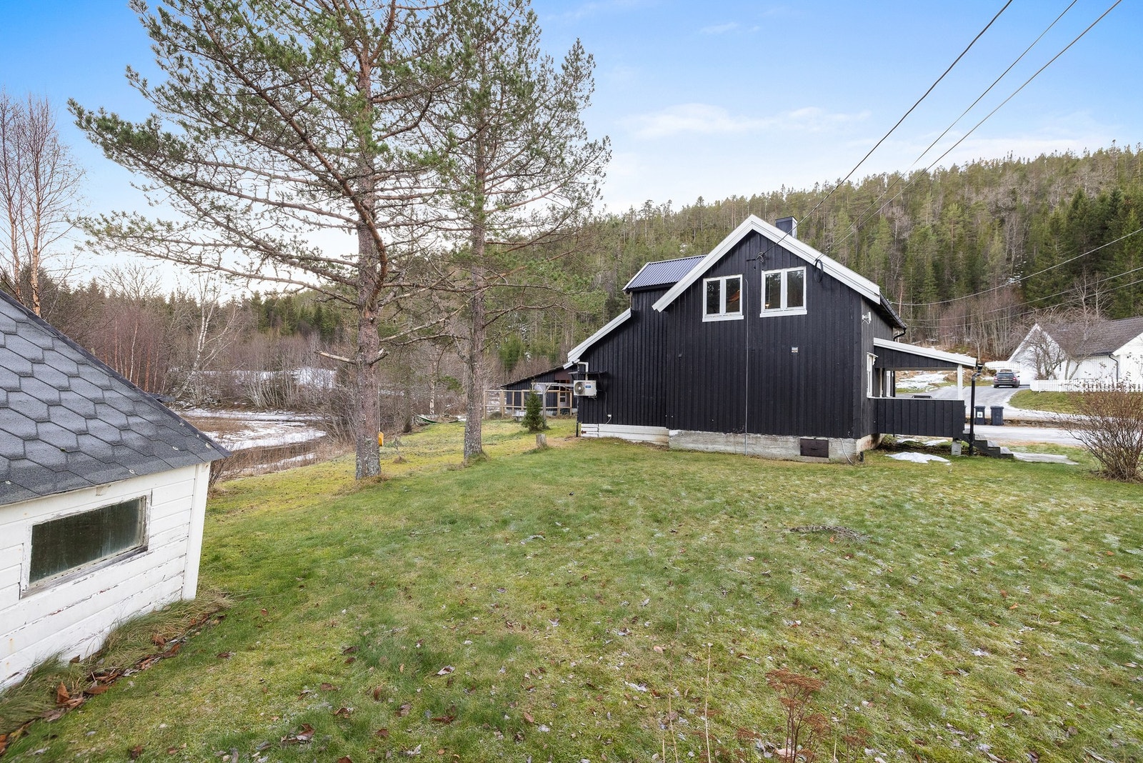 Tomten er opparbeidet med grusede kjørearealer, plen og noe beplantning Galleribilde