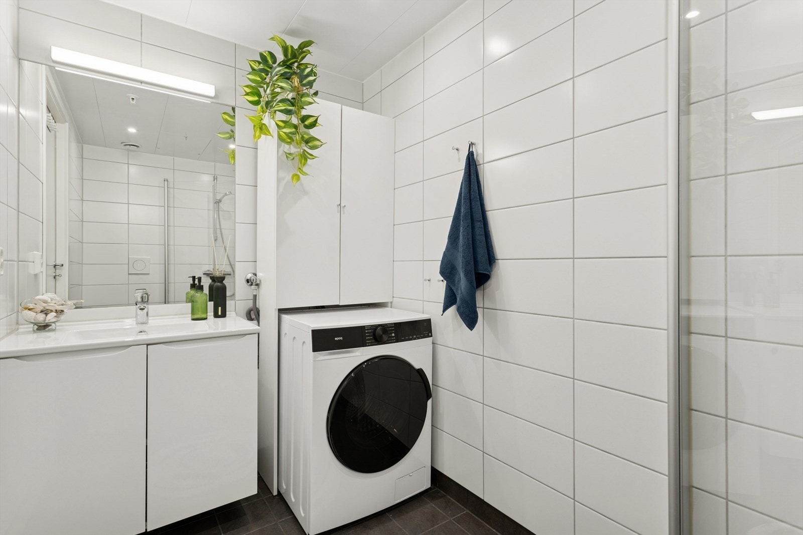 Badet er utstyrt med servant med innredning, dusjhjørne, toalett og opplegg for vaskemaskin. Galleribilde