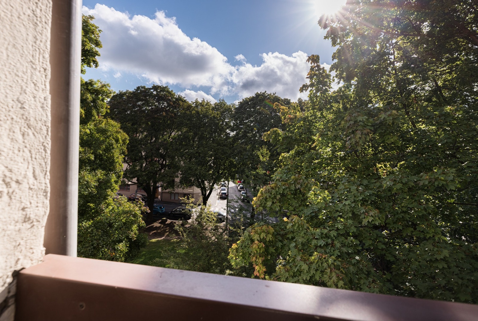 Leiligheten og balkongen vender ut mot sameiets bakgård og videre ut mot friområde. Grønn og frodig utsikt på sommertid. Galleribilde