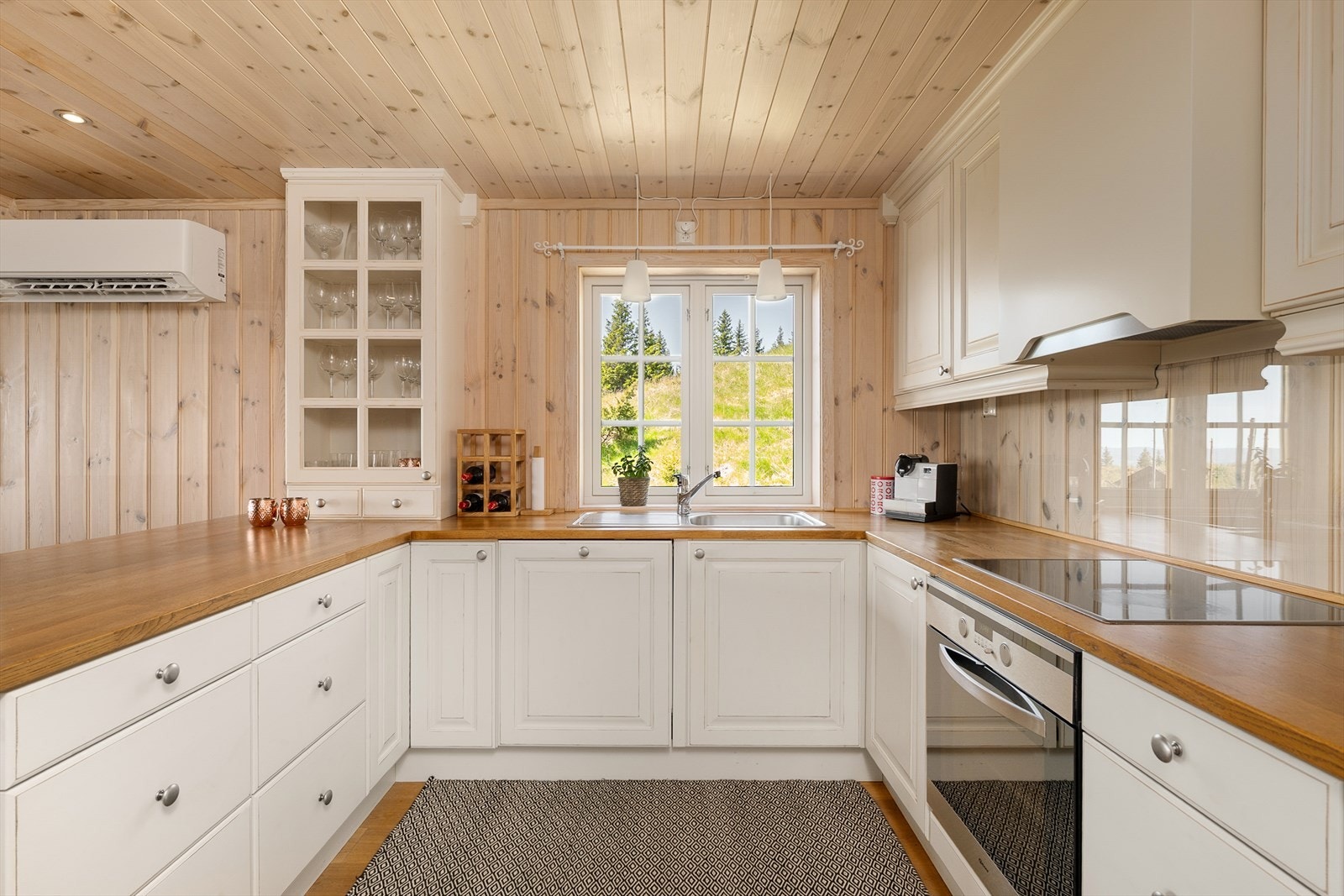 Innredningen er i en slags U-form der benken mot stua har barløsning og plass til krakker. Godt lys inn i rommet med vindu over kjøkkenbenken. Galleribilde