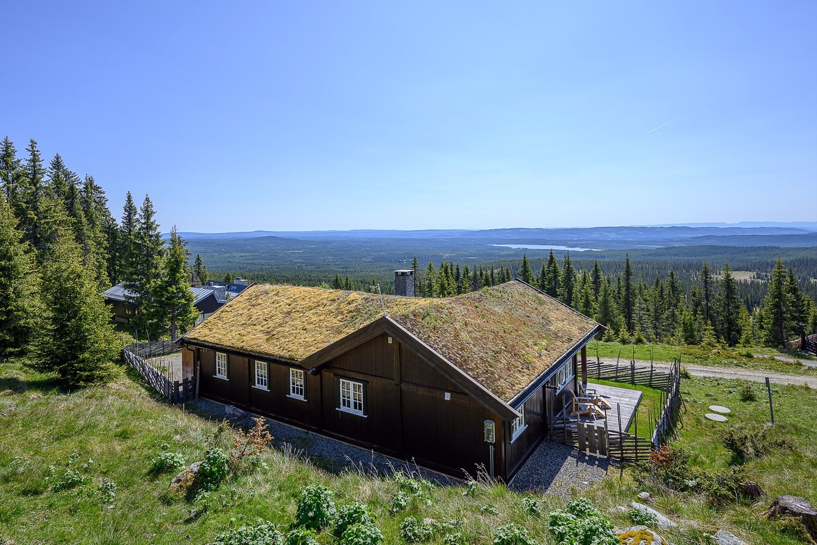 Hytta ligger i skrående terreng der området rundt i all hovedsak er naturtomt. Gressaraler innenfor skigarden. Galleribilde