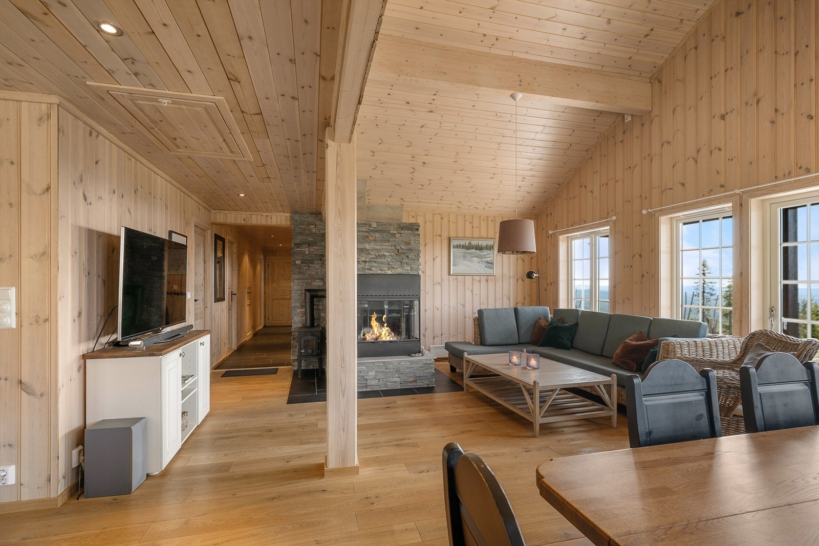 Det er god plass til både salong og langbord i hytta. Oppholdsrommet er sosialt og hyggelig med en åpen løsning mellom stue og kjøkken. Galleribilde