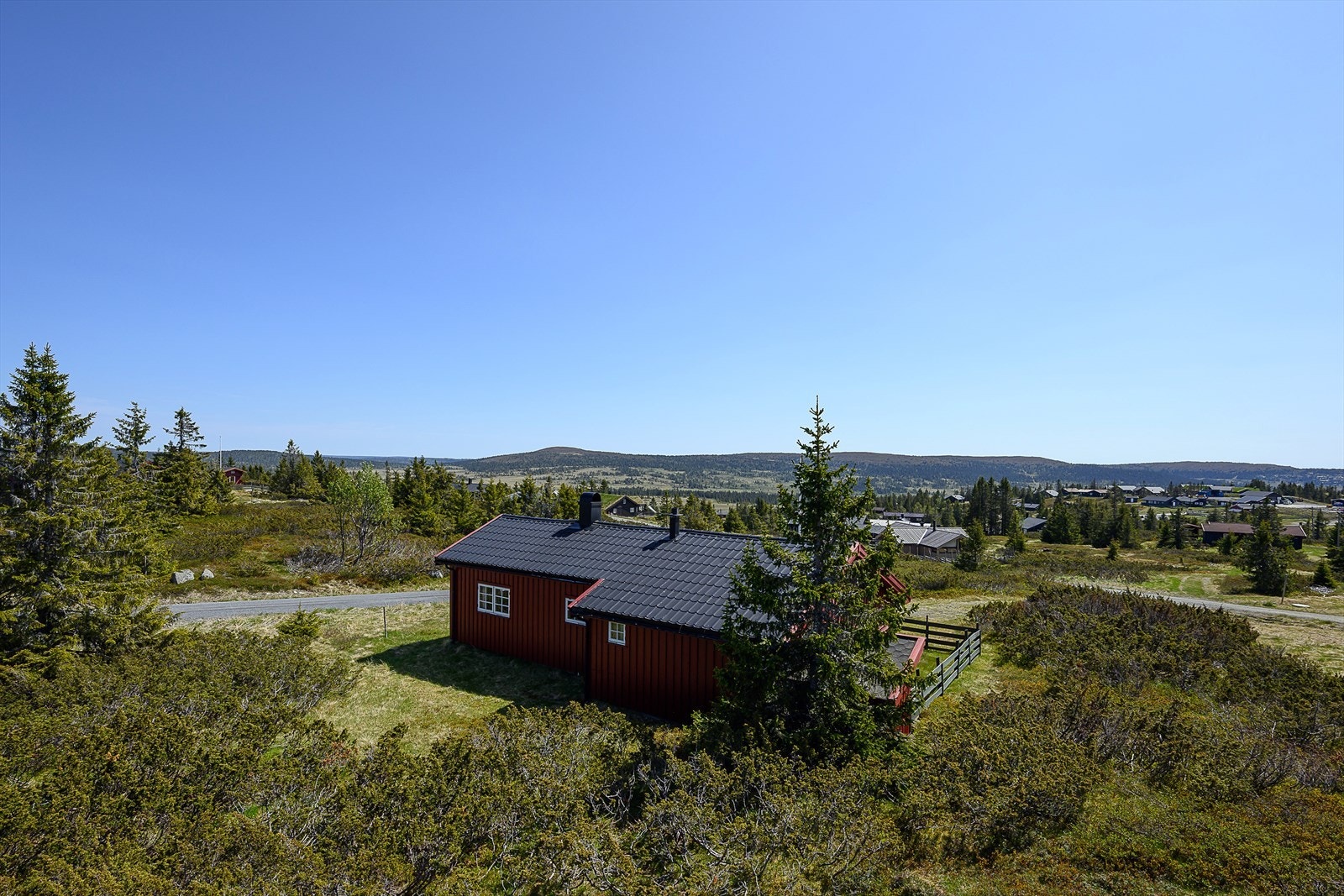 Hytta er omkranset av naturtomt og gressbakke. Galleribilde