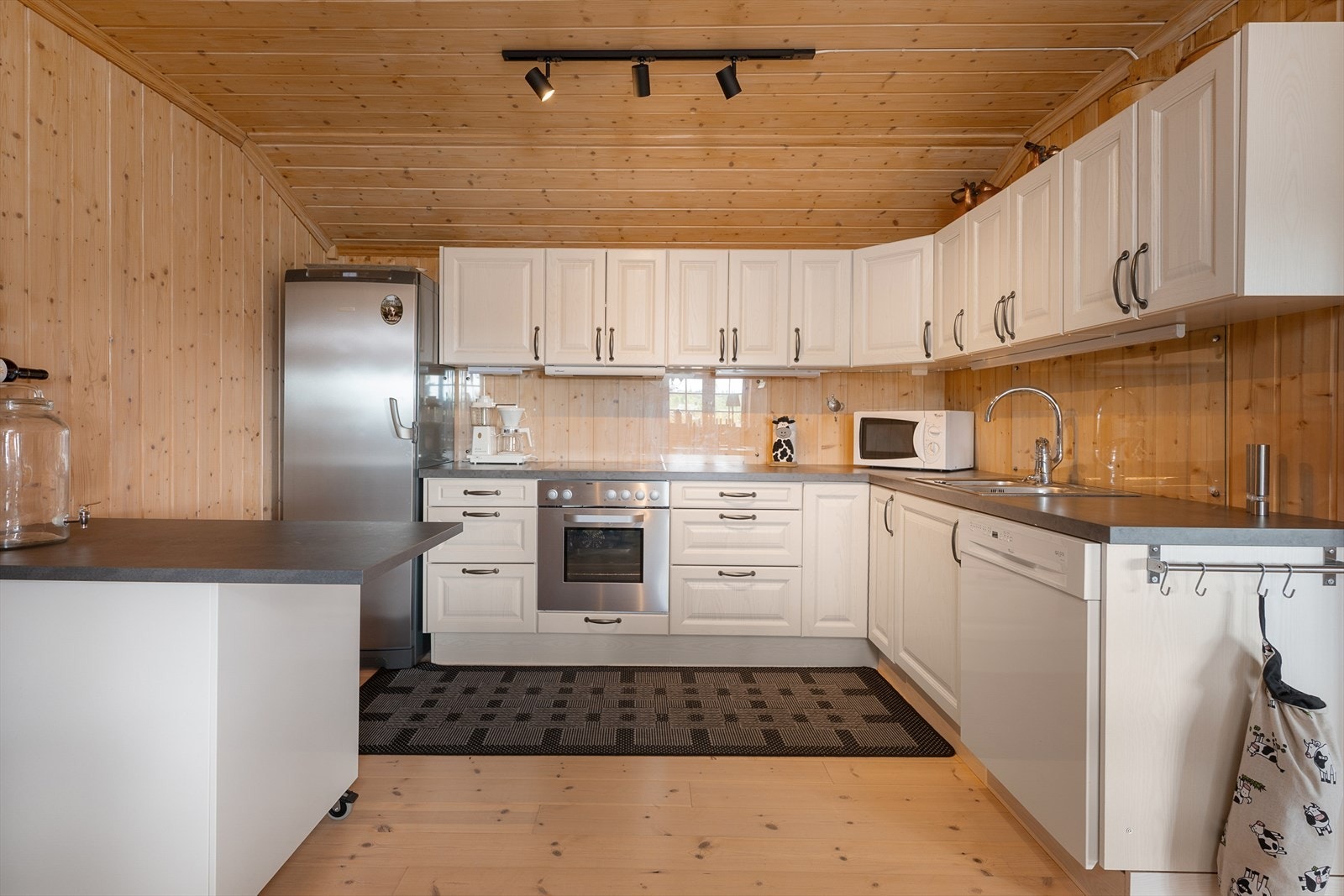 Kjøkkenet er praktisk og har integrert komfyr og plass til kjøleskap og oppvaskmaskin. Over-og underskap samt skuffer for oppbevaring. Galleribilde