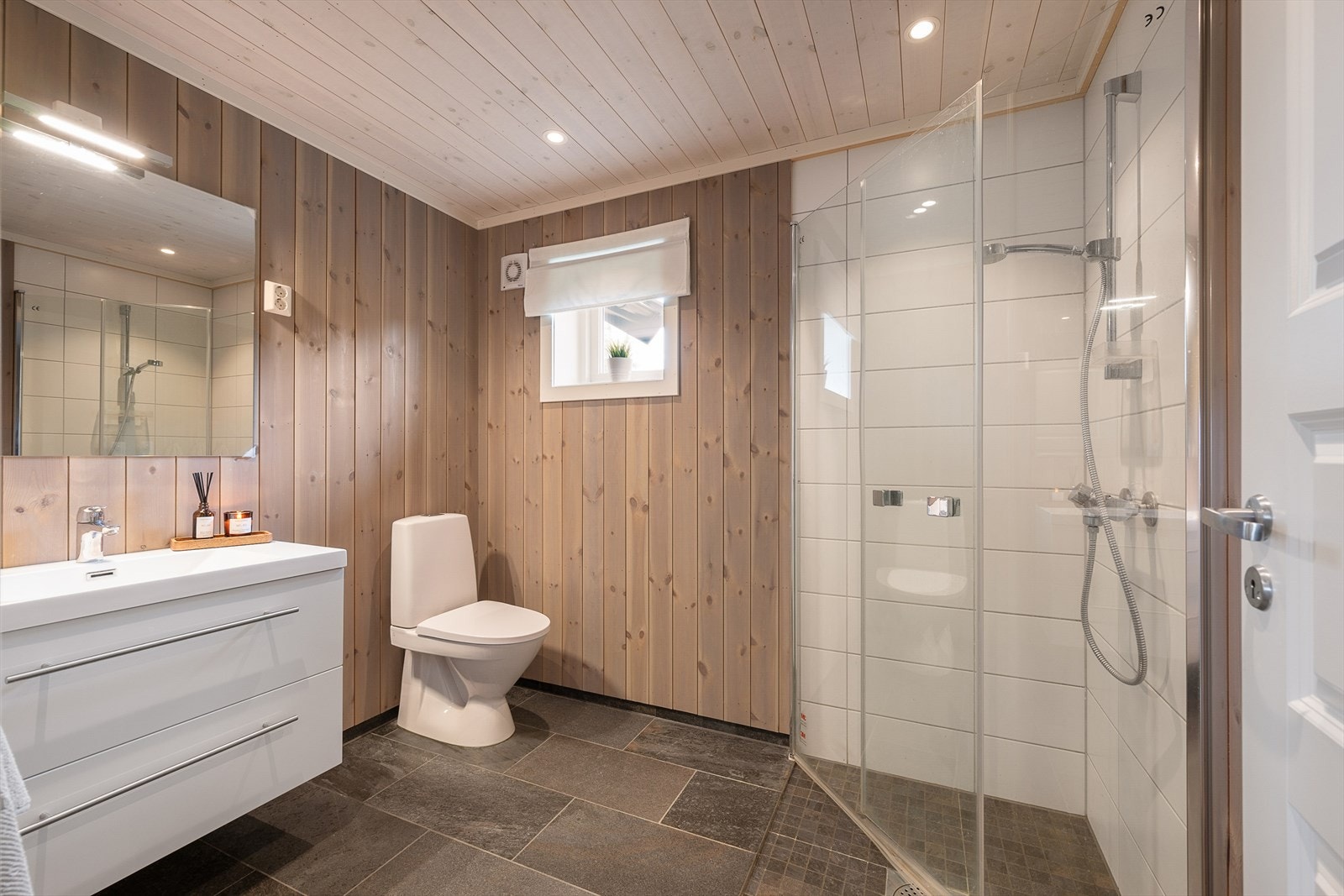 Pent og funksjonelt bad med dusj, servant i innredning og WC. Dusj har innfellbare glassdører. Galleribilde