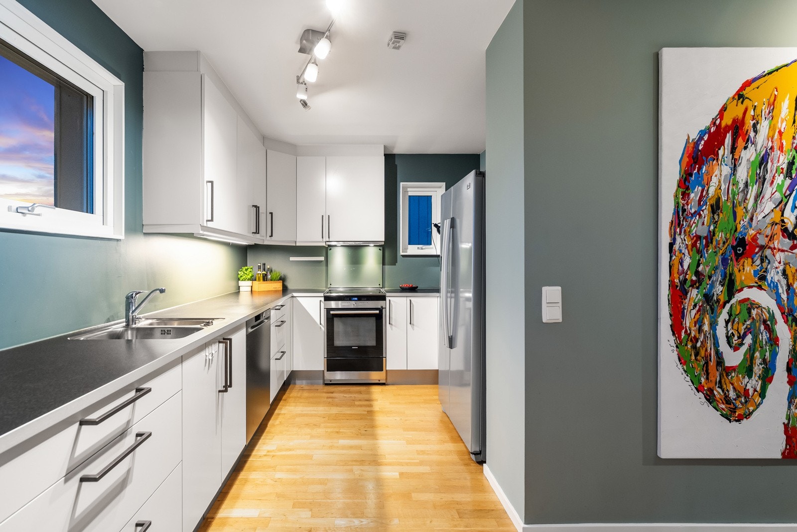 HTH kjøkkeninnredning med glatte fronter. Laminat benkeplate med planlimt kum i rustfritt stål. Ventilator med avtrekk gjennom yttervegg. Opplegg for oppvaskmaskin. Galleribilde