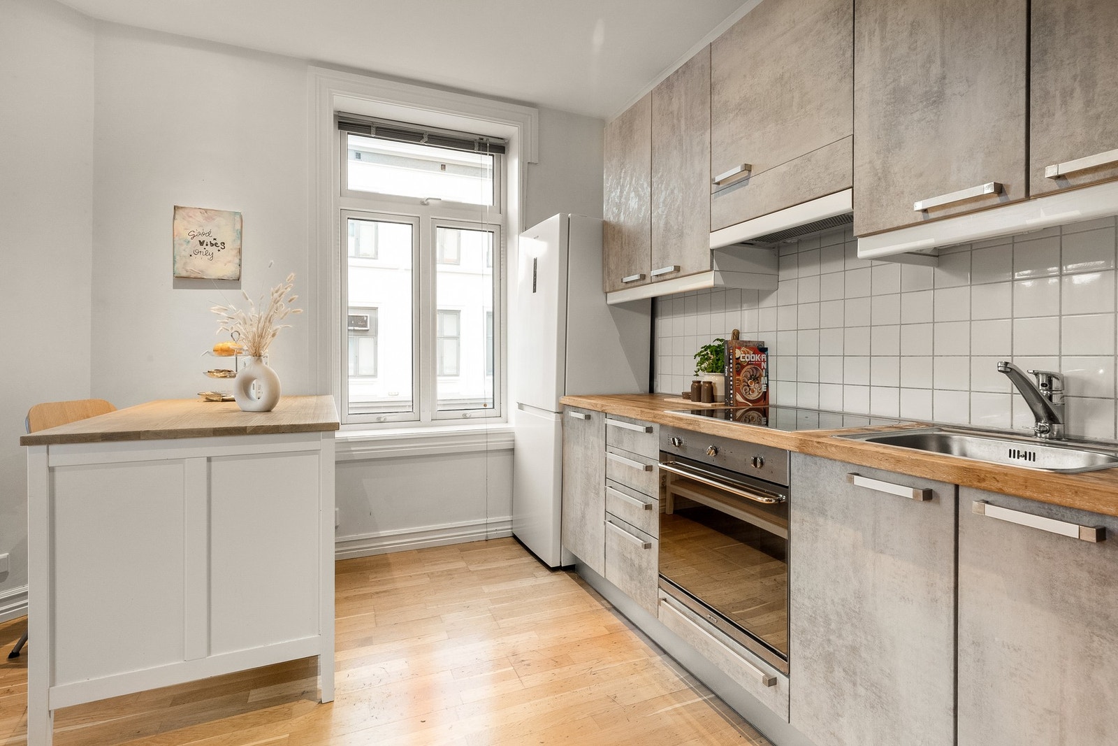 Lyst kjøkken fra 2006. Innredningen har glatte fronter kombinert med benkeplate av heltre med nedfelt kum i stål. Galleribilde