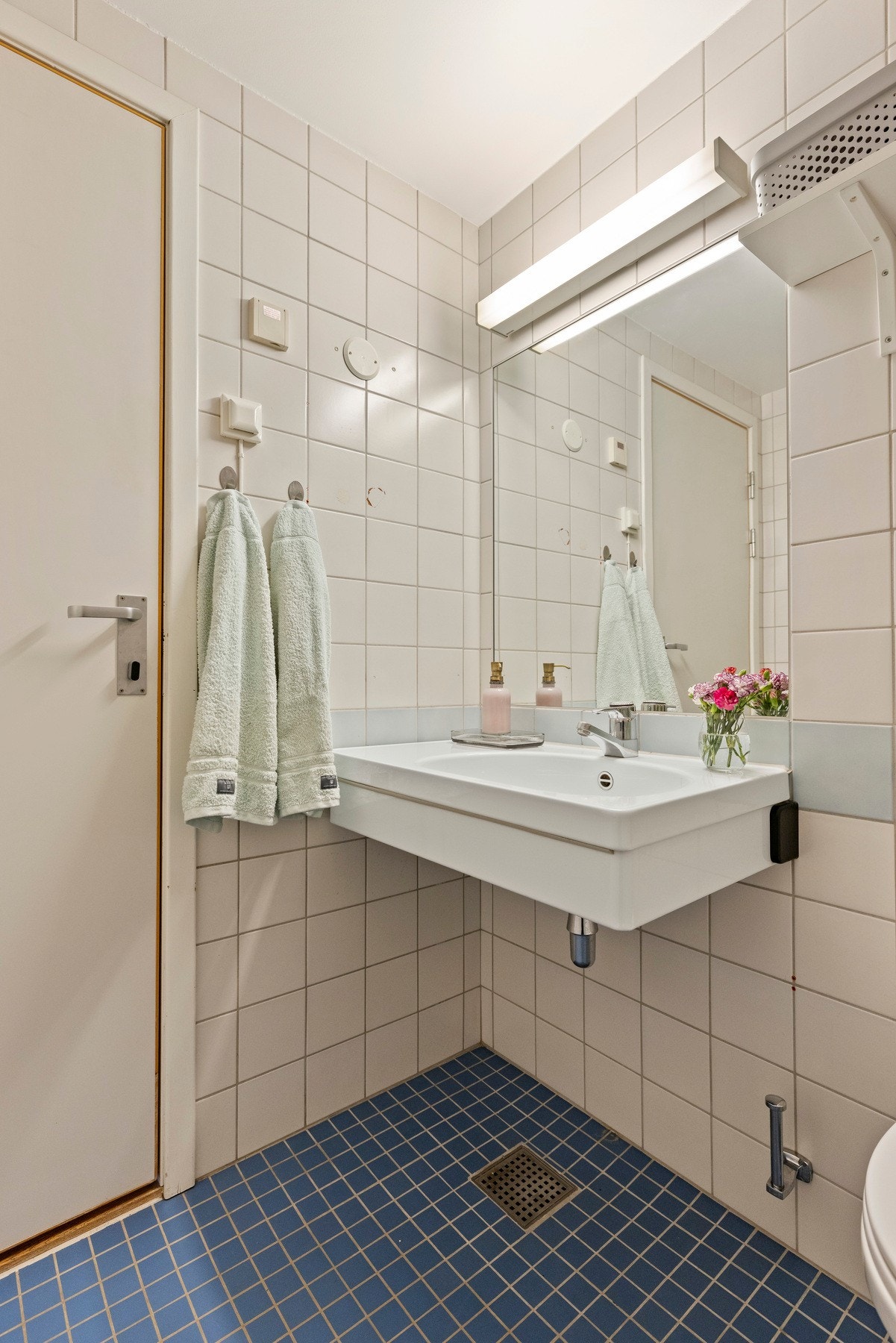 Badet er utstyrt med veggmontert toalett, badekar med dusjvegg samt servant med tilhørende skap, speil og belysning. Galleribilde