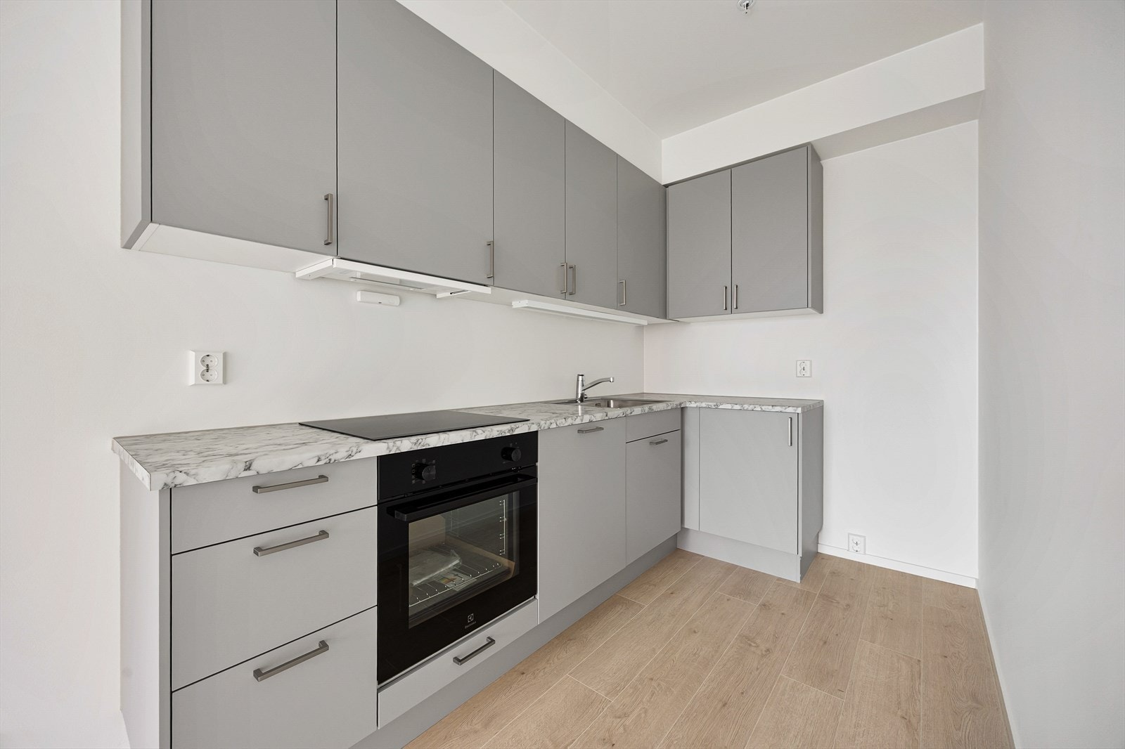 Kjøkkeninnredningen har glatte, grå fronter og laminatbenkeplate i marmor-look. Galleribilde