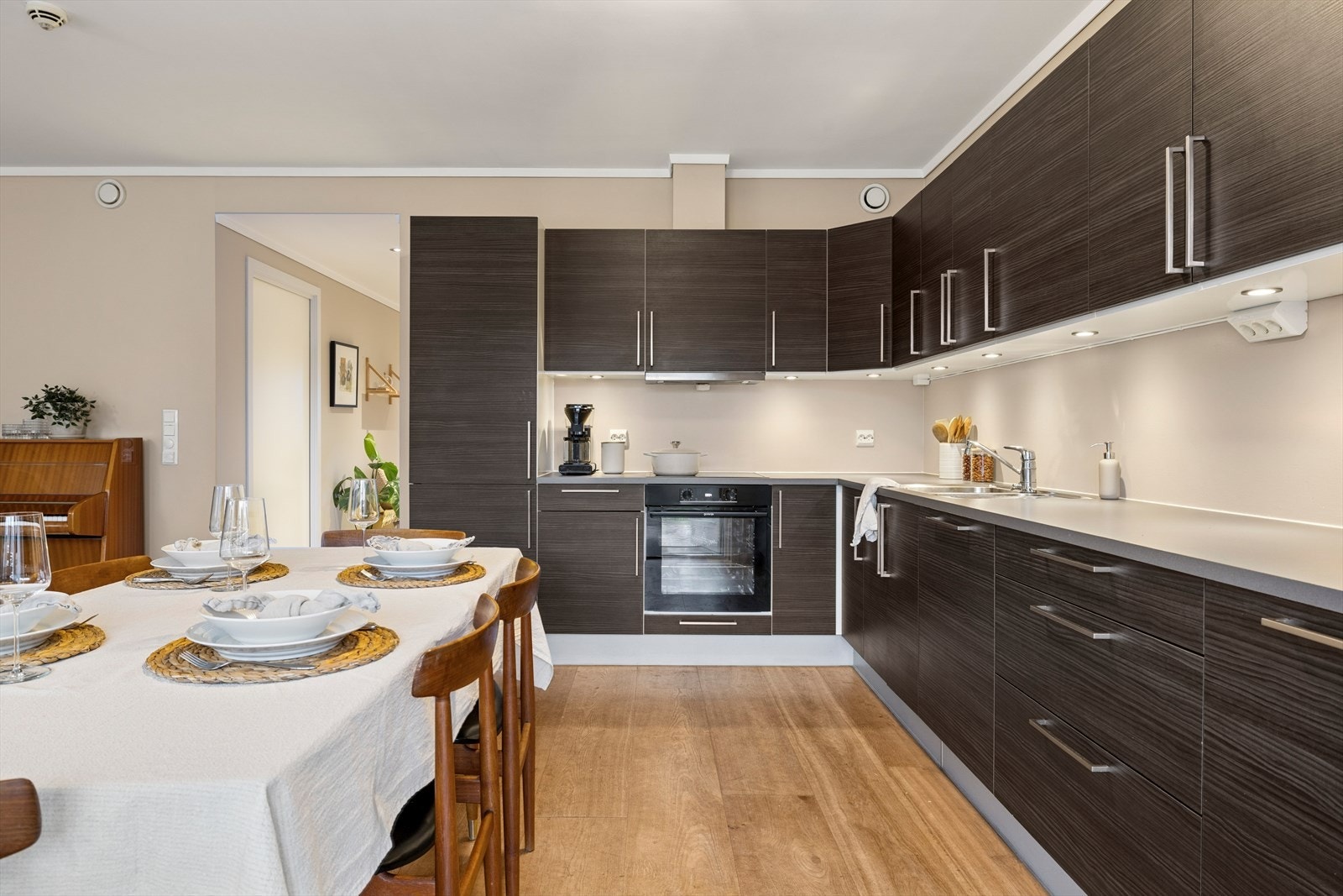 Kjøkkenets innredning har glatte fronter, godt med skap-/benkeplass og belysning under overskap. Galleribilde