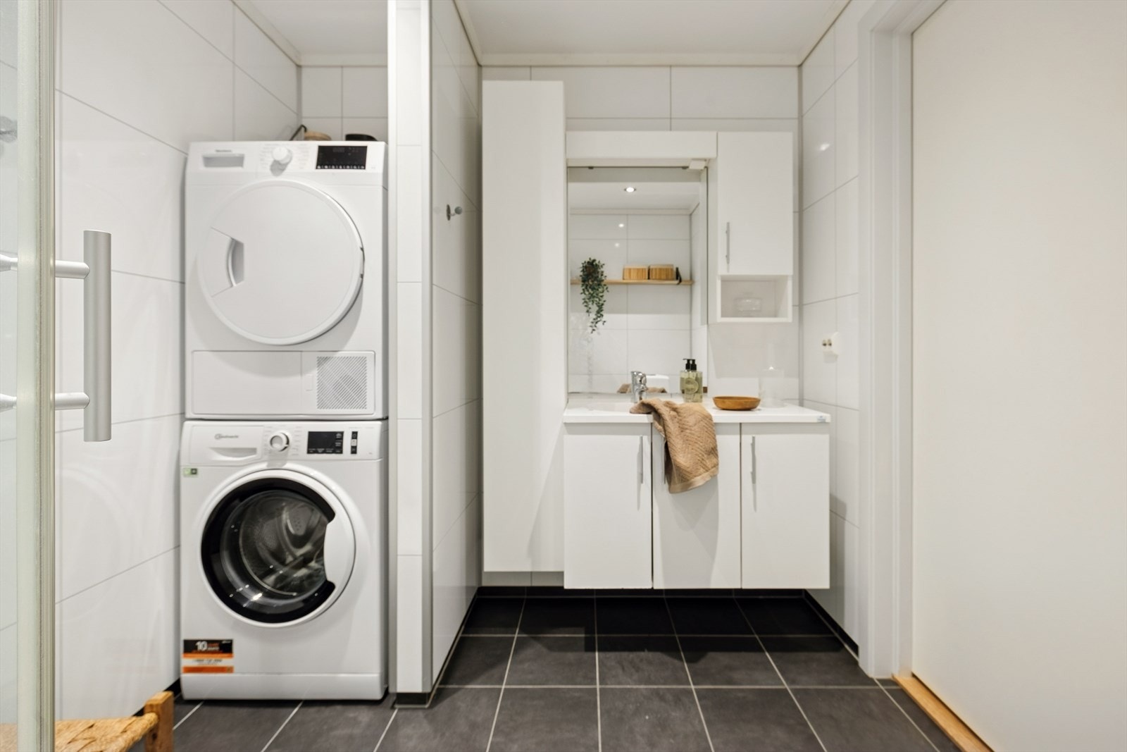 Badet har en baderomsinnredning med heldekkende servant, speil, toalett og dusjkabinett. Det er i tillegg opplegg for vaskemaskin og plass til tørketrommel i nisje på badet. Galleribilde