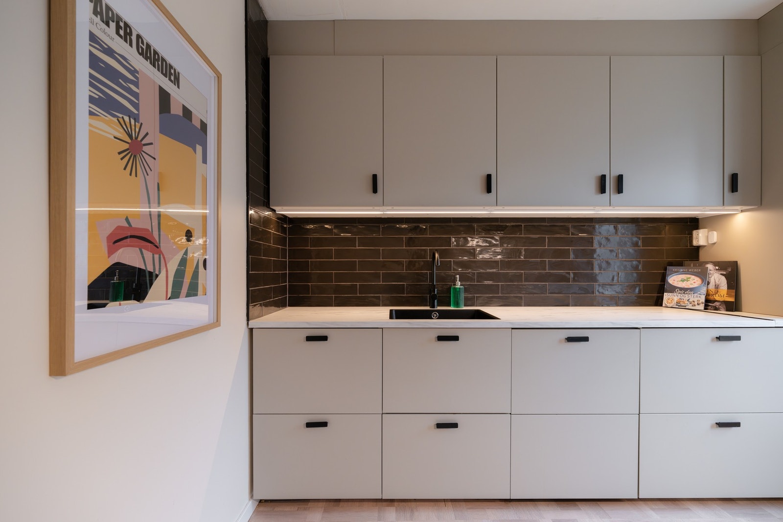 Mellom kjøkkenbenken og overskapene er det fliser, samt benkeskapsbelysning og stikkontakter. Galleribilde