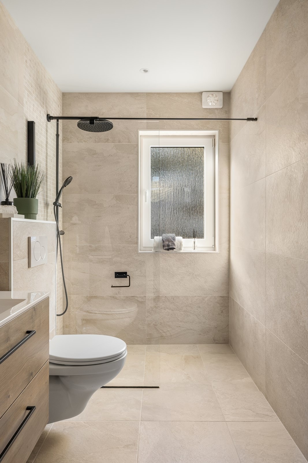 Dusjnisje med glassvegg, regnfallsdusj og en dekorativ mosaikkvegg. Galleribilde