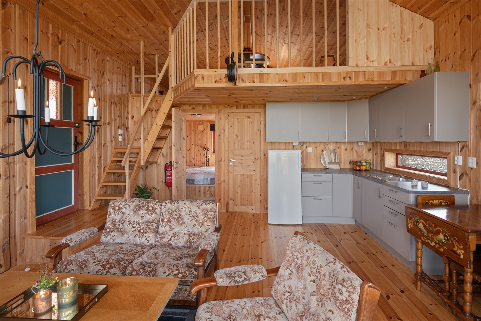 I den tilbygde delen på hytta er det en åpen løsning mellom stue og kjøkken og trapp opp til en åpen, romslig hems. Galleribilde