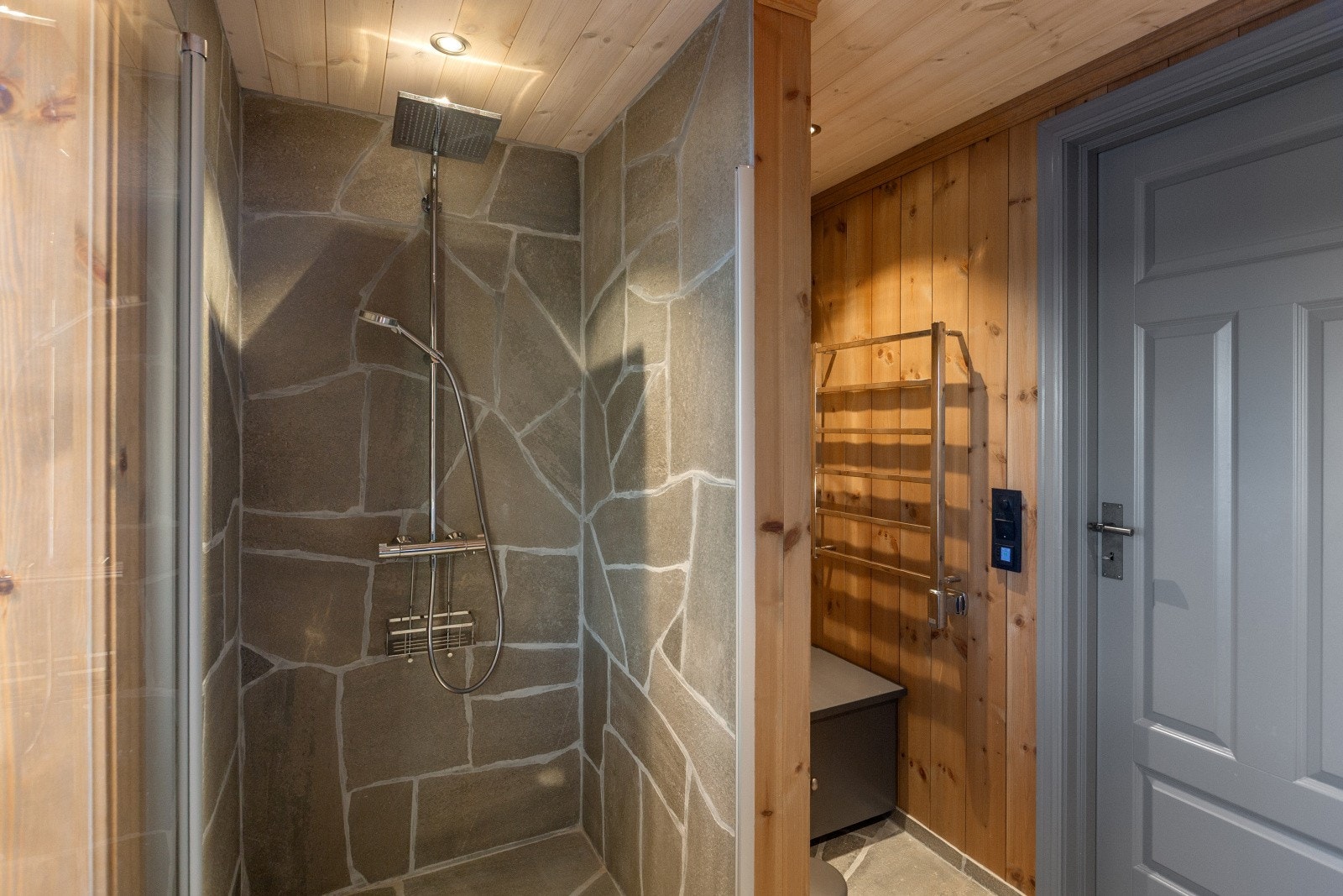 Det andre badet har innredning i heltre, toalett og stort dusjhjørne med glassdør og vegger kledd med skiferheller. Sittebenk av malt tre med skuff, samt håndklevarmer. Galleribilde