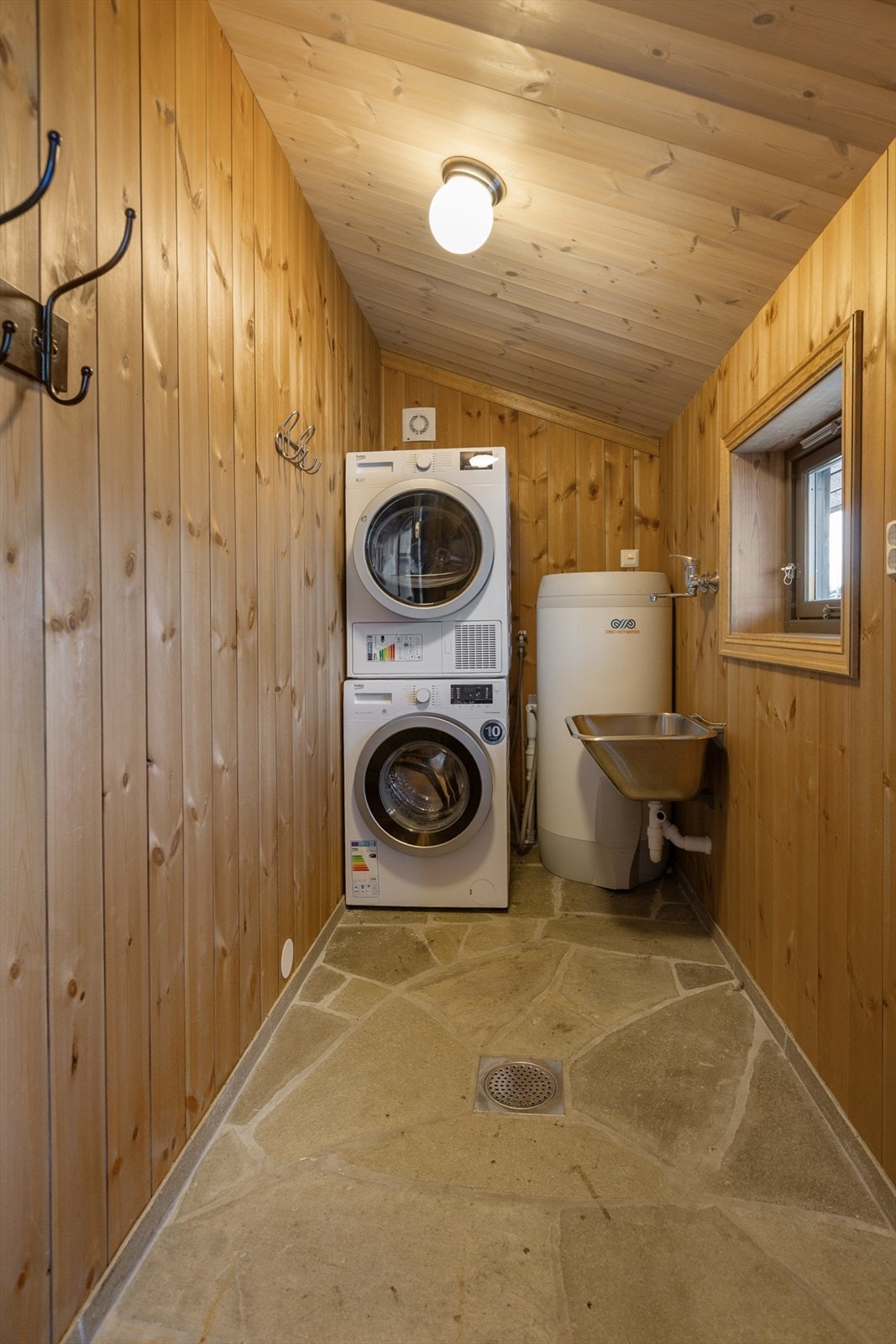 Fra inngangspartiet er det adkomst til vaskerom/teknisk rom og romslig utebod. Vaskerommet har utslagsvask i stål, varmtvannstank, samt opplegg for vaskemaskin og tørketrommel. Galleribilde