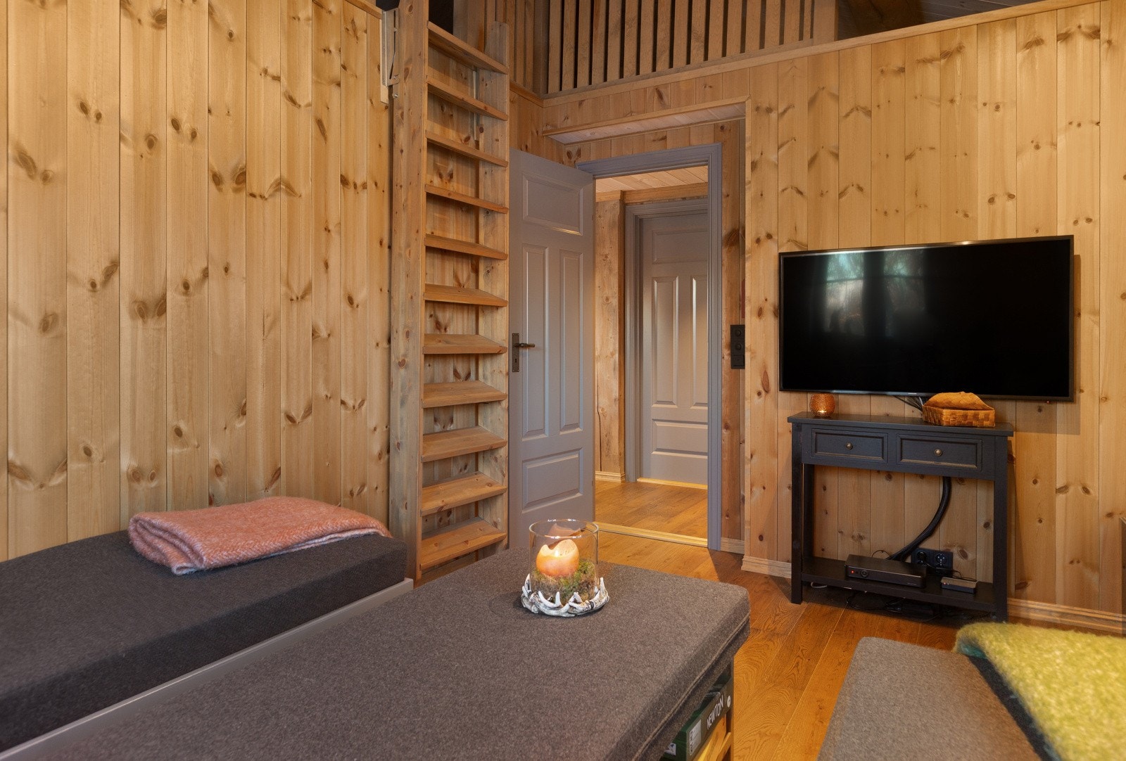 Rommet er innredet med tv, samt plassbygd sofa av malt tre med skuffer for oppbevaring. Galleribilde