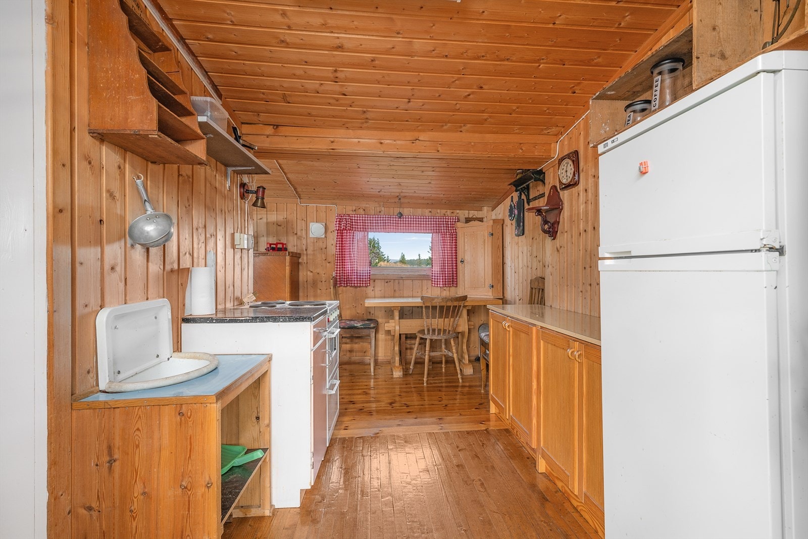 Enkel innredning på kjøkkenet med plass til kjøleskap. Trehvite fronter på innredningen. Galleribilde