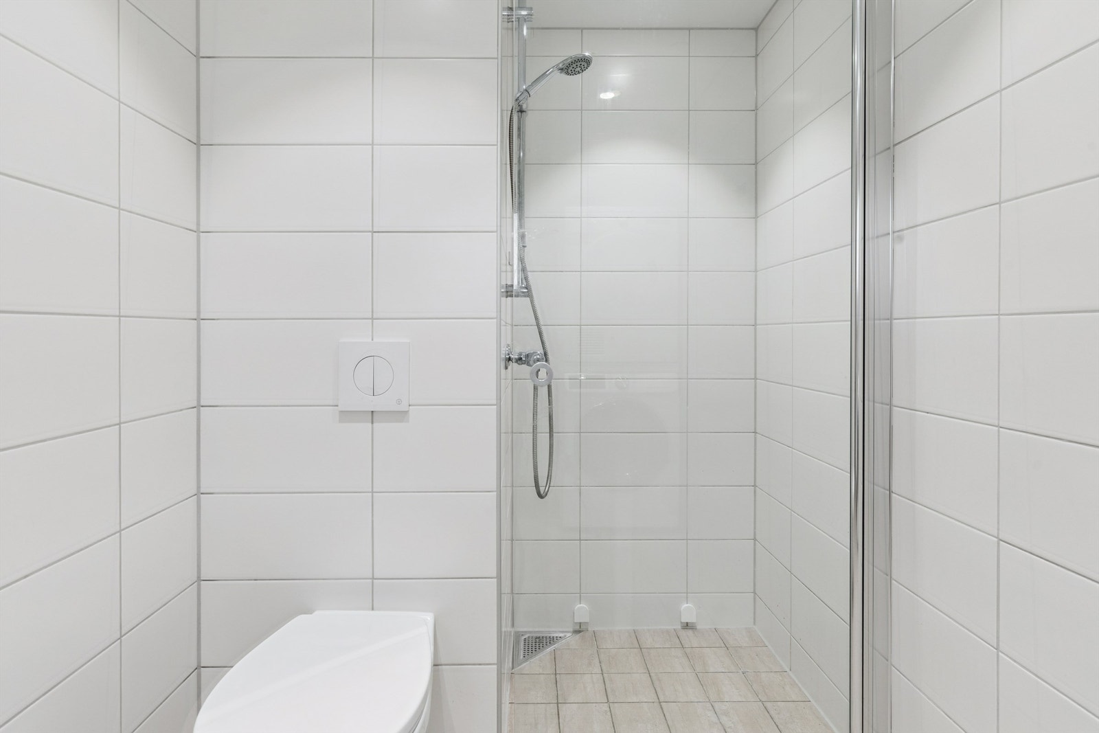 Egen dusjnisje med glassdør, og vegghengt toalett gir et rent uttrykk. Badet har banemembran og stålsluk. Galleribilde