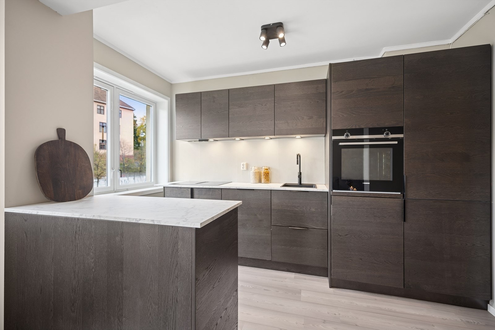 God belysning under overskap og praktiske plater på vegg over benkeskap. Her er det godt med oppbevaringsplass. Galleribilde