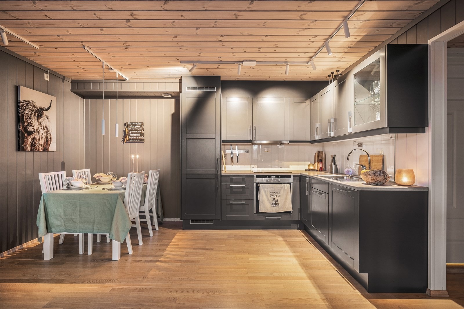 Stilrent kjøkken med sorte profilerte fronter og lys benkeplate med kjøkkenbeslag. Galleribilde