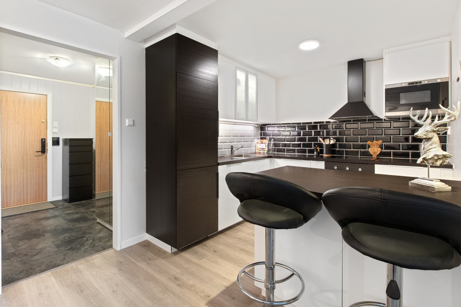 Kjøkkenet har glatte fronter og benkeplate av laminat, med integrerte hvitevarer som platetopp, komfyr, oppvaskmaskin, micro og kjøl/frys. Galleribilde