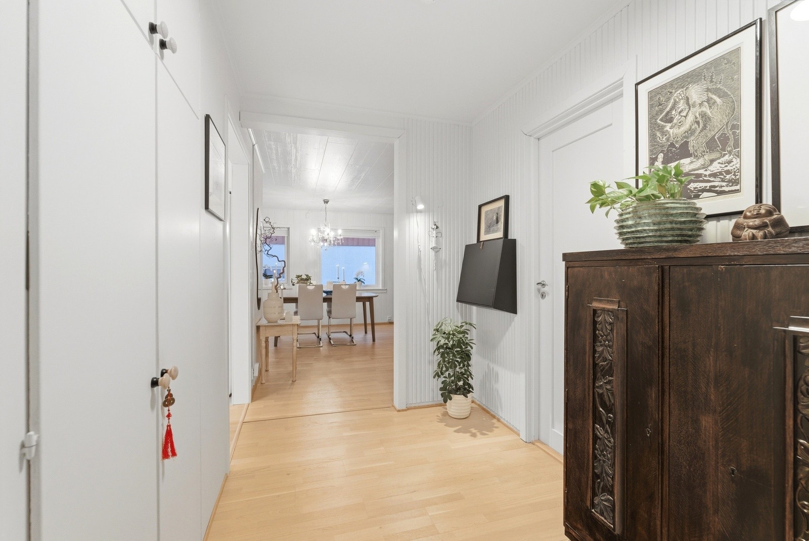 Entré/gang med oppbevaringsplass i plassbygde skap og oppheng langs vegg. Parkettgulv og lysmalte vegger. Galleribilde