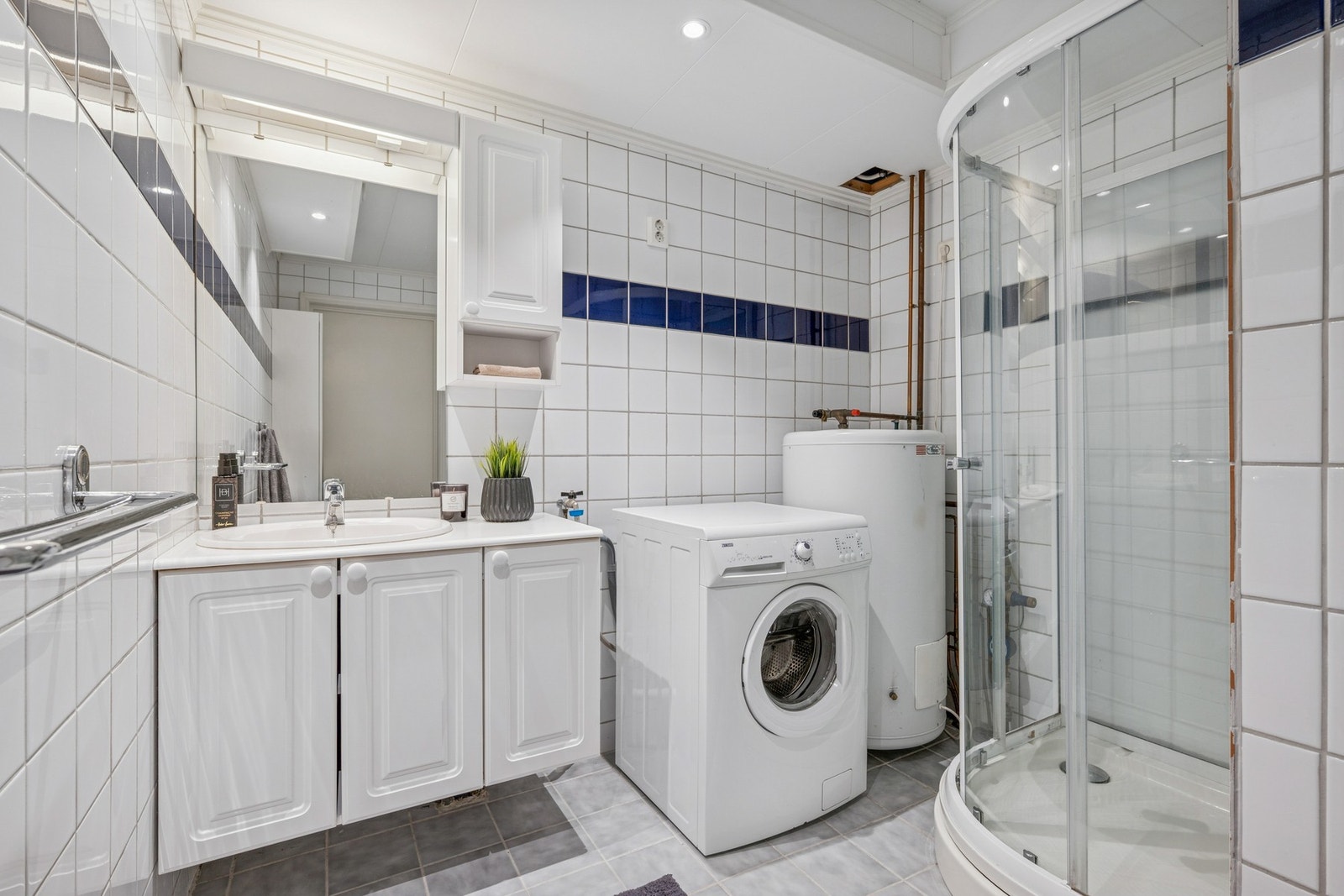 Baderommet i hybelen er utstyrt med servantinnredning, speil med belysning og dusjkabinett. Galleribilde