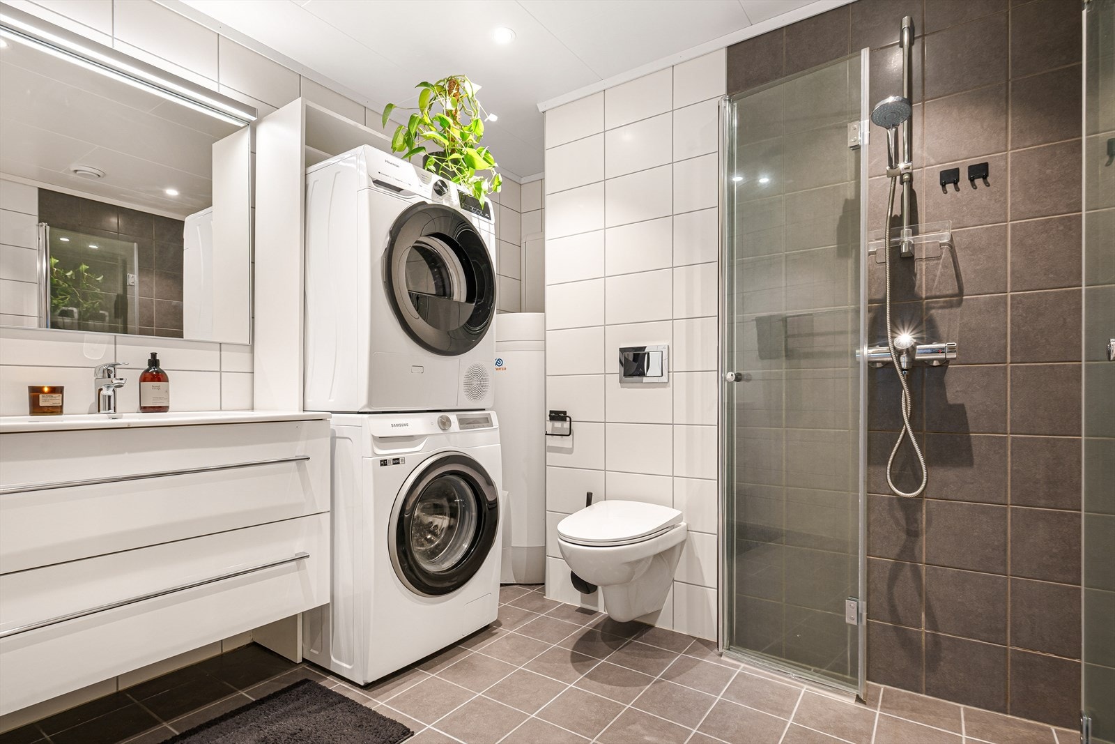 Helfliset bad innredet med heldekkende servant, veggmontert toalett, innfeltbare dusjvegger/hjørne i herdet glass og opplegg for vaskemaskin. Galleribilde