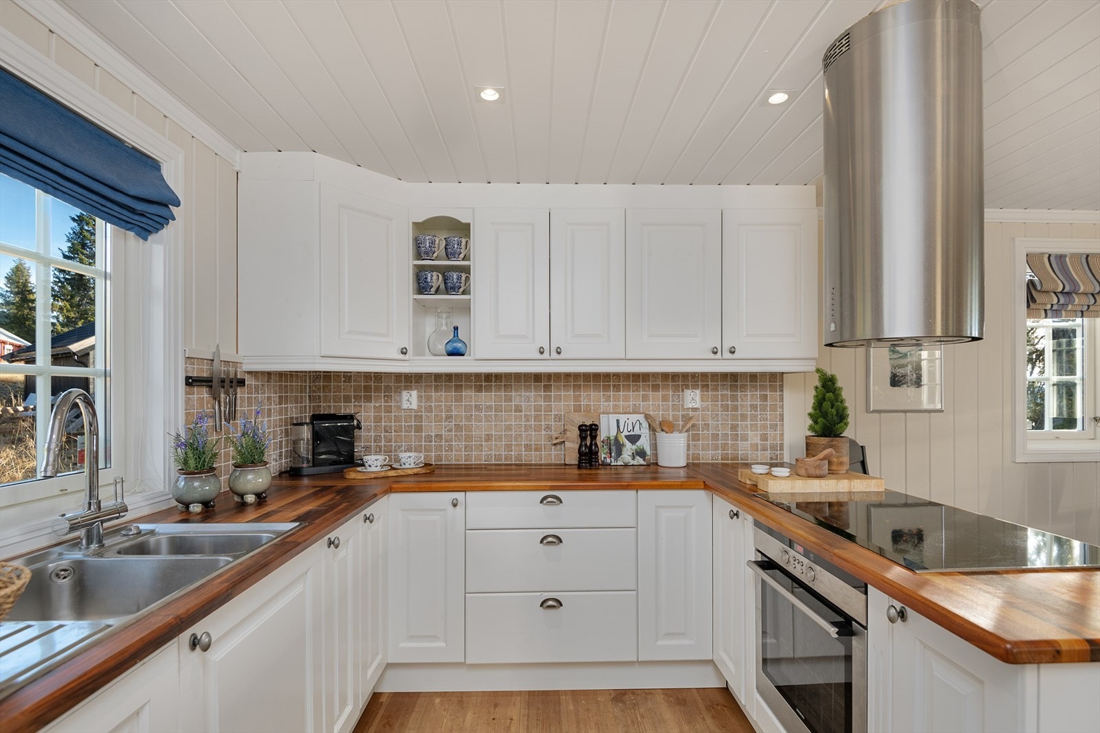 Lyst, pent og romslig kjøkken har rikelig med skap-og benkeplass. Malte fronter med enkel profilering. Fint lys inn over kjøkkenbenken. Galleribilde