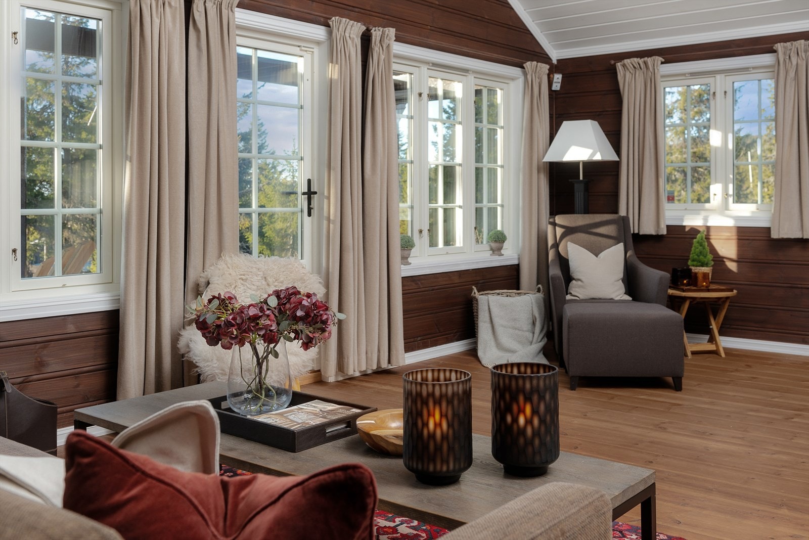 Det er en tidløs stil i stua med lune gulv og vegger beiset i en mørk bruntone. Fine møbleringsmuligheter. Galleribilde