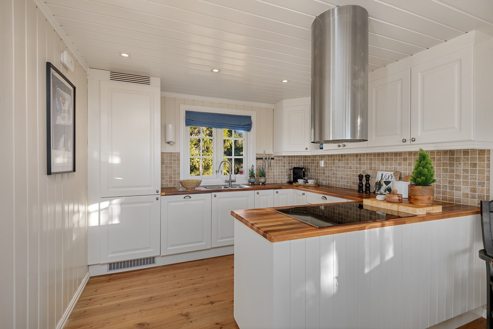 Innredningen har integrerte hvitevarer. Det er fin kontakt mellom kjøkkenet og spiseplassen. Galleribilde