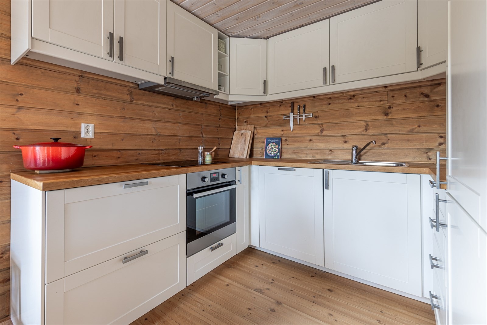 Innredet med profilerte fronter med integrerte hvitevarer som stekovn, steketopp, kjøl/fryseskap, vaskemaskin, oppvaskmaskin og mekanisk avtrekksvifte over stekesonen Galleribilde