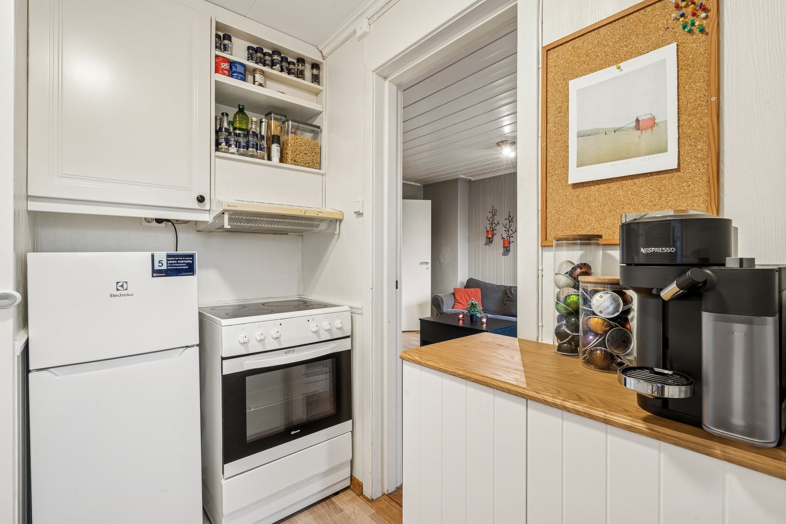 Benkeskapsbelysning og stikkontakter under overskap. Nedfelt oppvaskkum av rustfritt stål med ett-greps armatur. Komfyr med keramisk platetopp. Mekanisk kjøkkenventilator med kullfilter. Frittstående kjøleskap og fryser. Galleribilde