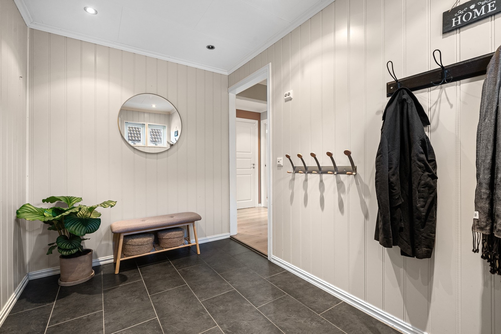 Inngangsparti med fliset gulv og praktiske knagger for oppheng av yttertøy. Galleribilde