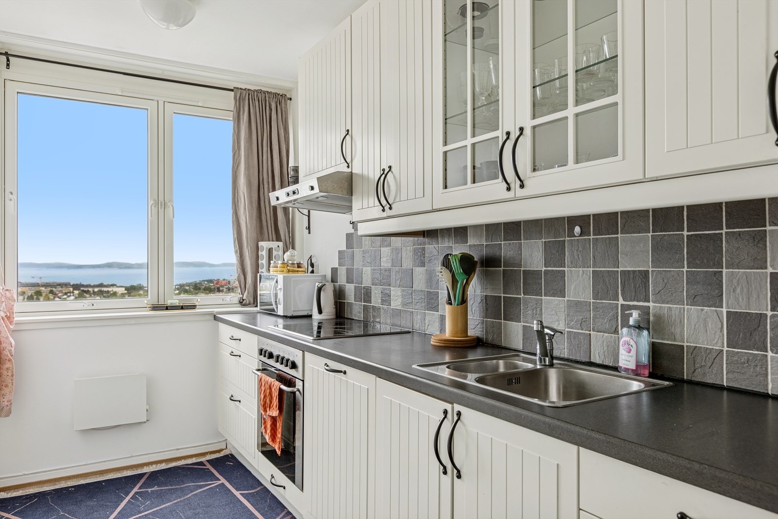 Lyst og pent kjøkken med integrert platetopp, stekeovn, oppvaskmaskin og kjøl/fryseskap. Galleribilde